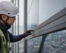 Technician inspecting an aged sealant joint on a curtain wall facade