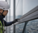 Technician inspecting an aged sealant joint on a curtain wall facade